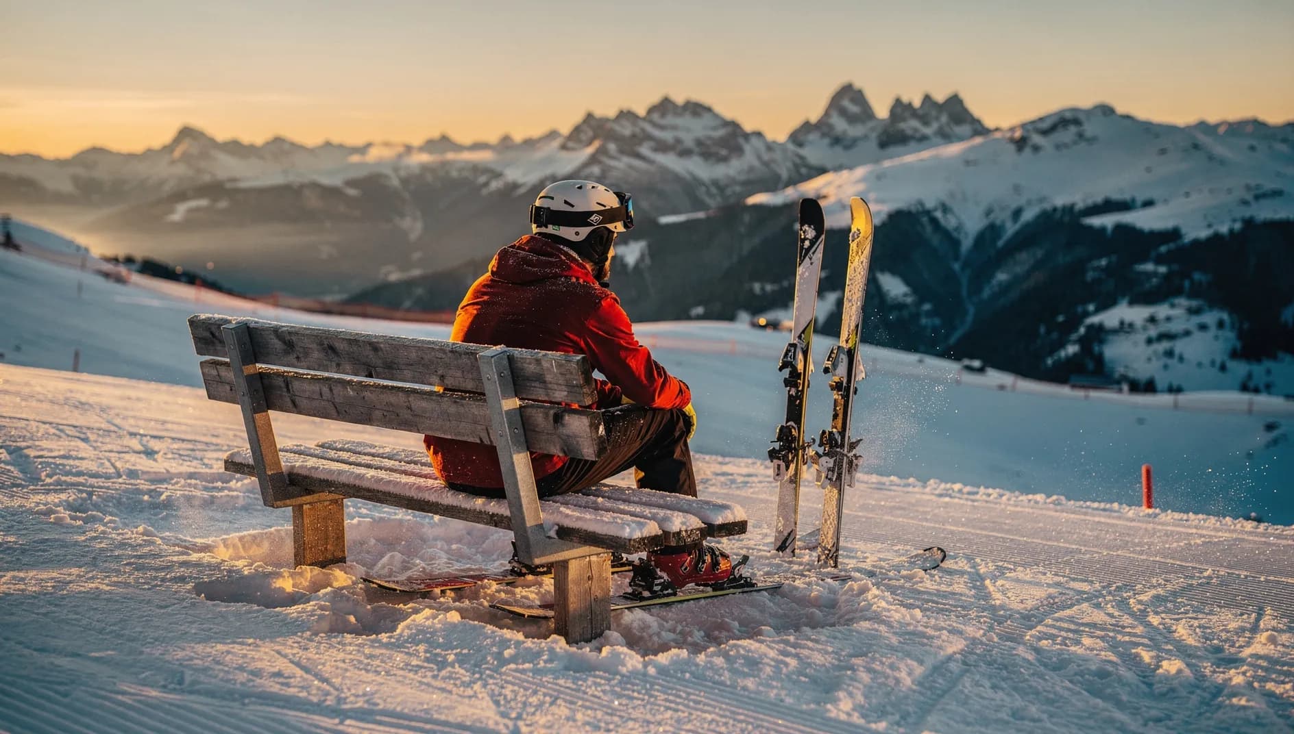 Skifahrer macht Pause auf einer Bank am Pistenrand